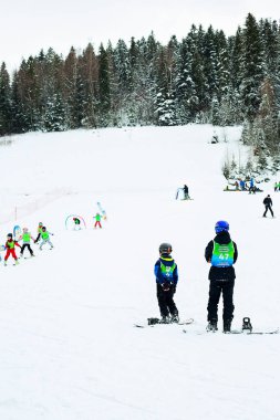Ski instructor and kids at ski school, in Poland Karpathians. Forest in the background.