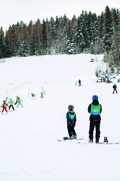 Ski instructor and kids at ski school, in Poland Karpathians. Forest in the background.