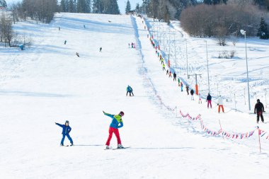 Bialka Tatrzanska, Polonya - 12 Şubat 2023: Tatra Dağlarındaki Hornikow Wierch Kayak İstasyonu. Turistler ve aşağı kayak. Kayak pistinin hazırlanması için gerekli ekipman. Geleneksel binalar