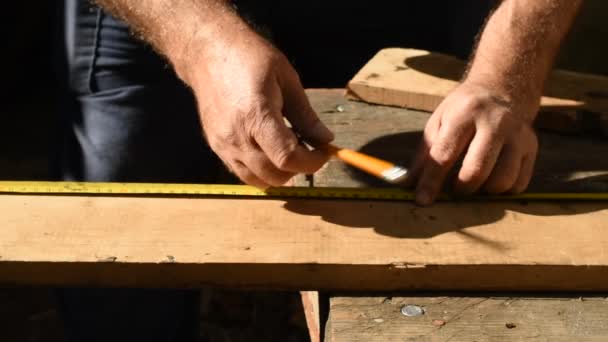 工人用胶带测量长板上所需的尺寸 用铅笔做记号 用尺子和铅笔划一条线 以划掉所需的一块 — 图库视频影像