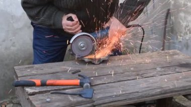 Video, bir işçinin elinde öğütücü tutarak metali nasıl kestiğini gösteriyor. Kıvılcımlar görünür.