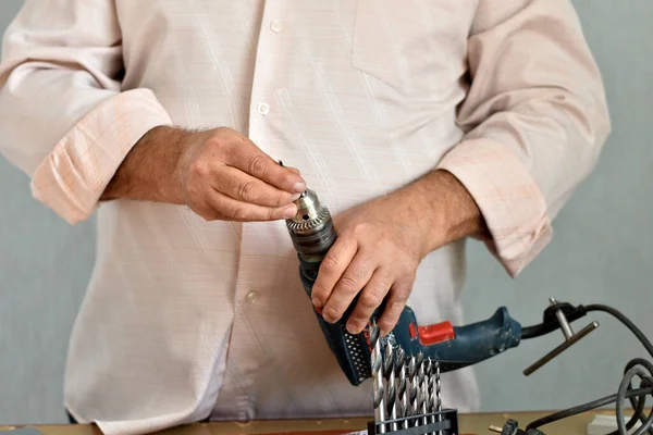 The picture shows a man holding a drill with one hand and inserting the drill into the drill with the other.