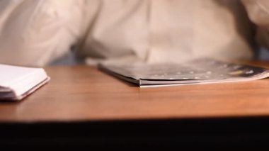 Masada duran resimli dergi sayfalarını karıştıran erkek ellerinin yakın çekimi.