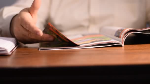 男性の手のクローズアップは テーブルの上に横たわる雑誌を残して — ストック動画