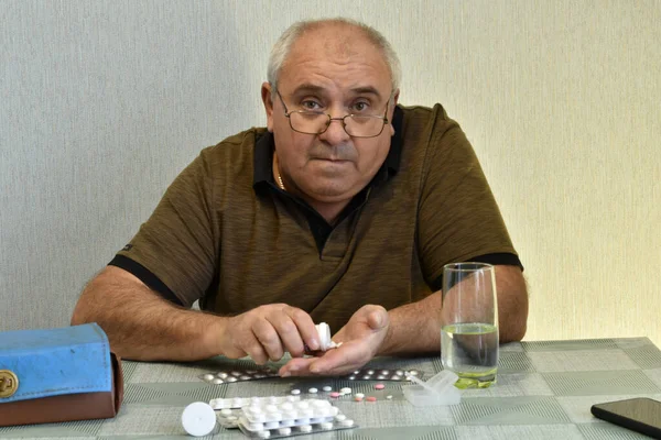 Stole Paczki Pigułek Mężczyzna Siedzi Przy Stole Próbuje Wyjąć Tabletki — Zdjęcie stockowe