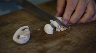 Aşçı kesme tahtasına geniş bir bıçakla mantar keser..