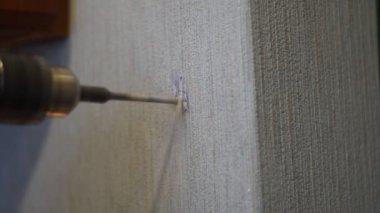 Duvarda elektrikli bir alet ve matkap kullanılarak delik açılır..