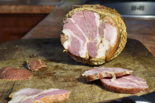 A large piece of low-fat boiled pork and pieces cut from this meat lie on a cutting board.