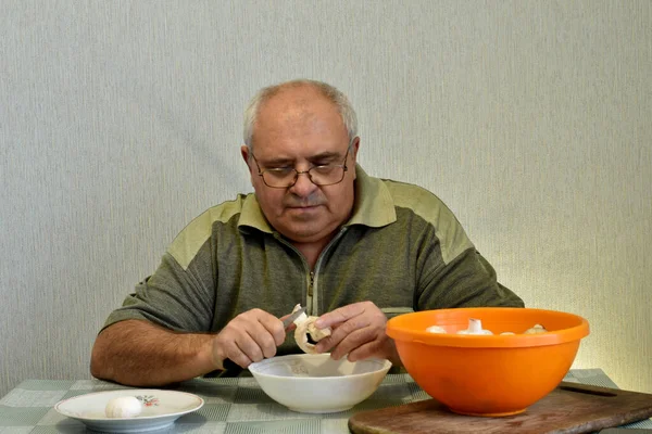 Zdjęciu Mężczyzna Siedzący Przy Stole Obierający Grzyby Nożem Wyciąga Pomarańczowej — Zdjęcie stockowe