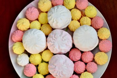 Resim, yukarıdan çekilen şekerlerin, şekerlerin ve kremaların olduğu bir tabağı gösteriyor..