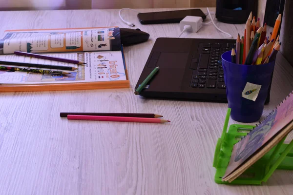 The picture shows a mess left on the table in the office, pencils, a laptop, a magazine.