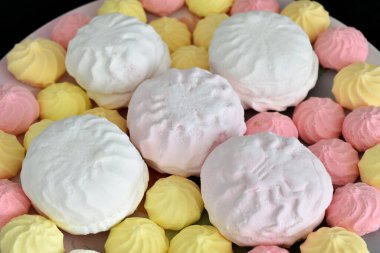 Resimde, şekerler, krema beyazı, pembe ve marşmelov düz bir tabakta uzanıyorlar..