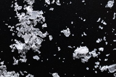 Saçılmış tuz, şeffaf kristalleri, siyah arka planda ilginç bir şekil oluşturdu..