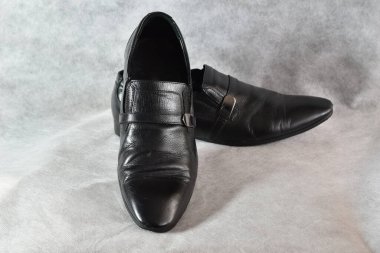 Resim beyaz arka planda siyah bir çift deri ayakkabıyı gösteriyor..