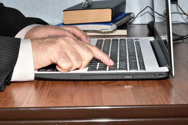 A man works at a computer, he types text on the keyboard with his finger.