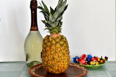 Resim, şenlikli ürünleri, köpüklü şarabı, ananası ve tatlıları gösteriyor..