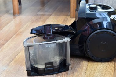 In the picture, there is a vacuum cleaner body and a dust collector on the floor.