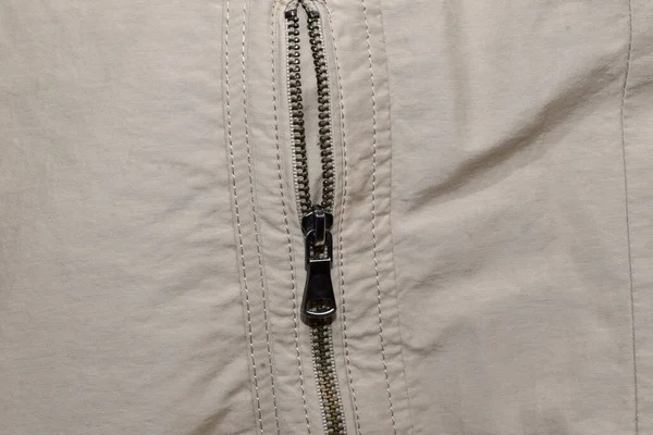 The picture shows a metal zipper with a lock on a light fabric men\'s jacket.