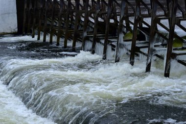 Dam on the river and seething, foaming water falling from the dam.