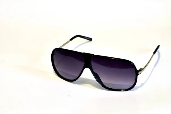 Fashionable sunglasses with dark glasses in a thin frame lie on a white background.