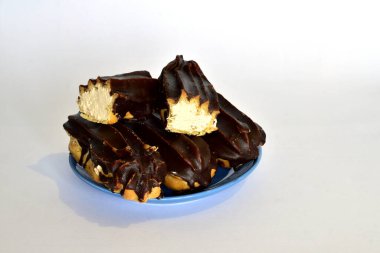 Whole and cut eclairs covered with chocolate lie on a plate.