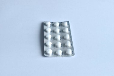 On a white background lies a long pack of pills in four rows of white.