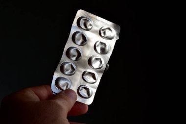 A package without pills is held by a man's hand.