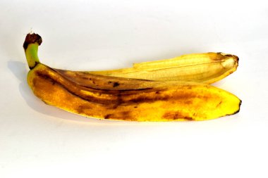 Banana peel in dark spots lies on a white background.
