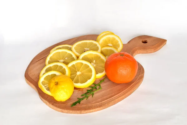 图上是一块切割板 上面放着一个多汁的黄色柠檬 切割成环状和一个橘红色 — 图库照片