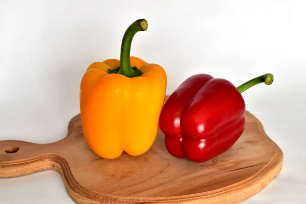 In the picture, there are sweet yellow and red bell peppers on a cutting board.