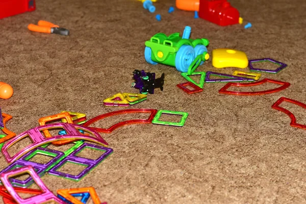 On the floor in the room, children\'s toys are scattered and not removed after the game.