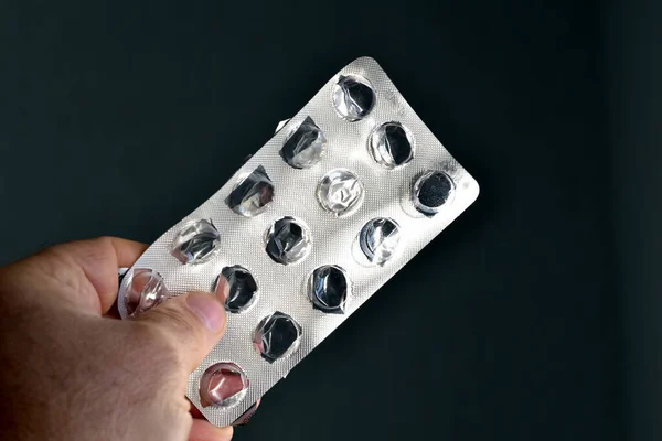 A man's hand holds a package without pills.