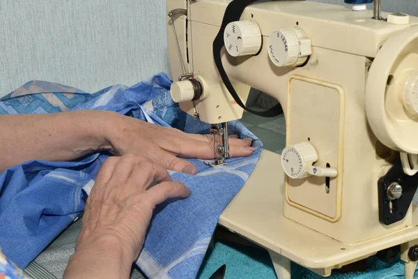 帮助缝纫机缝制两种面料的女裁缝的手 — 图库照片