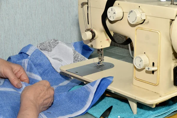 女裁缝的手连接着两块布料 放在缝纫机前面的桌子上 — 图库照片