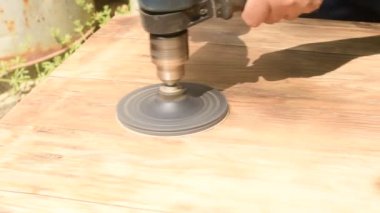 Videoda, bir işçi zımpara kağıdıyla ahşap bir yüzeyi zımparalarken görülebilir, zımpara kağıdı matkapla döndürülen öğütme çarkına bağlıdır..