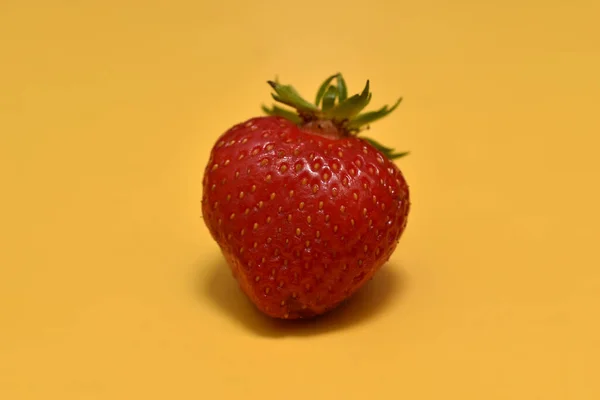 Eine Einzige Rote Beere Namens Erdbeere Liegt Auf Gelbem Hintergrund — Stockfoto