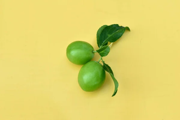 Zielone Śliwki Zielony Liść Gałęzi Leżą Żółtym Tle — Zdjęcie stockowe