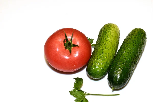 青い肌の2つの熟したキュウリと緑の小枝のある赤いトマトは白い背景にあります — ストック写真