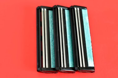 Üç blokluk yeniden kullanılabilir tıraş bıçakları pembe arka planda jiletsiz yatıyor..