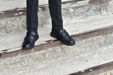 Genç adamın ayakları, taş bir merdivende duran deri ayakkabılarla nallandı..