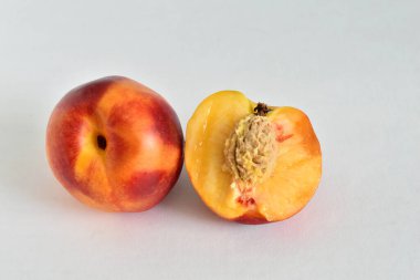 Beyaz arka planda nektarin meyveleri yatıyor, biri bütün, diğeri kesik..