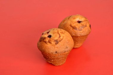 Kırmızı arka planda kuru üzümlü ve reçelli iki kek..