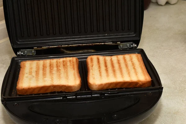 The picture shows an electric grill with toasted toast for making sandwiches.