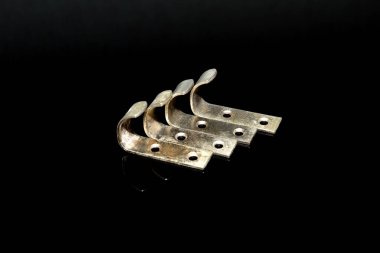 Siyah arka planda, mobilyalarda kullanılan kancalar bir sırada yatar..