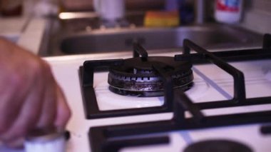 Gaz sobasının kapağını açarak, adam ocağın gazını yakıyor..