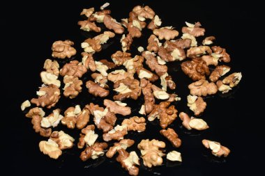 Ceviz taneleri siyah arka planda kaotik bir şekilde yatar..