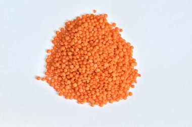 Beyaz arka planda kırmızı mercimek taneciklerinden oluşan bir tepe uzanıyor..