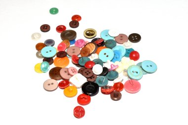 Farklı boyutlarda renkli düğmeler beyaz arkaplanda bir yığın içinde uzanır.