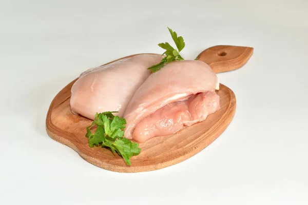 There is raw chicken meat and chicken breasts on the cutting board. The meat is ready to cook.