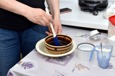 Bir kadın, çikolatalı şekerlemeleri derin bir tabakta kek yapmak için karıştırır..